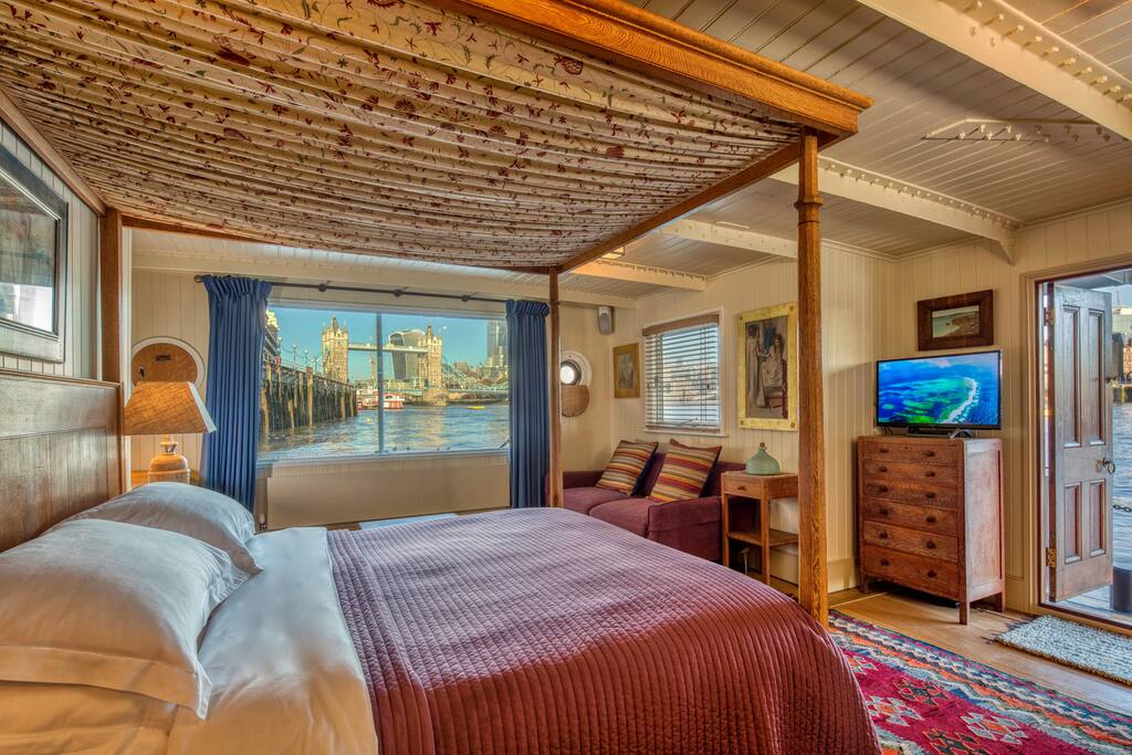 Tower Bridge Houseboat: Master Cabin 1. Remote controlled electric curtains reveal the view from the Heal's 1920's oak four poster bed