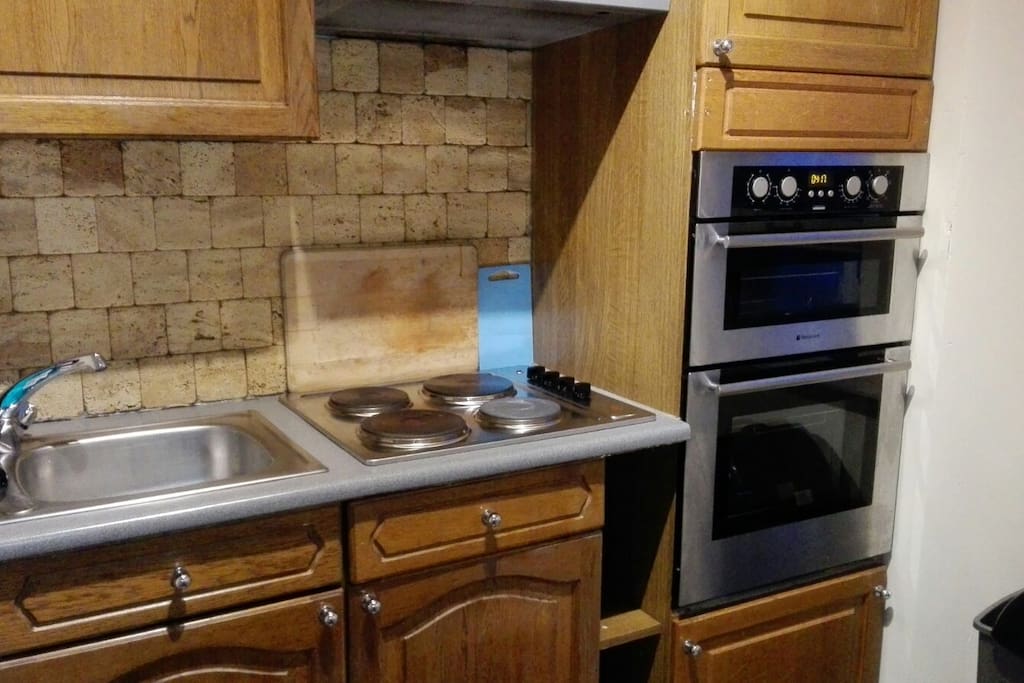 Rear view of the kitchen with sink, 4 cook fires, 2 ovens (small and big with grill) and storage space available.
