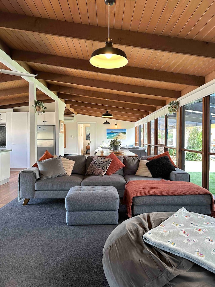 Large, open-plan lounge, dining, and kitchen area with beautiful exposed beams and a comfortable couch, plus a second living space for extra relaxation and privacy
