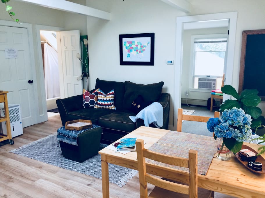 Plenty of comfortable seating in the main room. Bathroom and bedroom both open up to the living area with high ceilings, large skylight and well-loved plants.