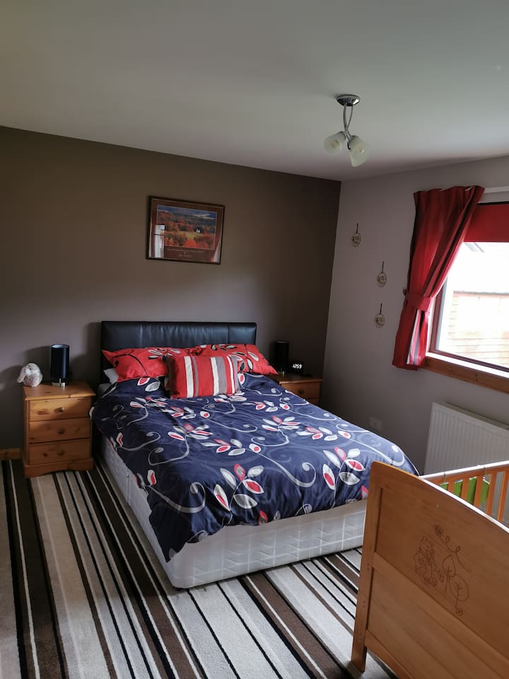 Amplio dormitorio doble con cuna.  Tiene almacenamiento/iluminación junto a la cama y un gran armario empotrado. 