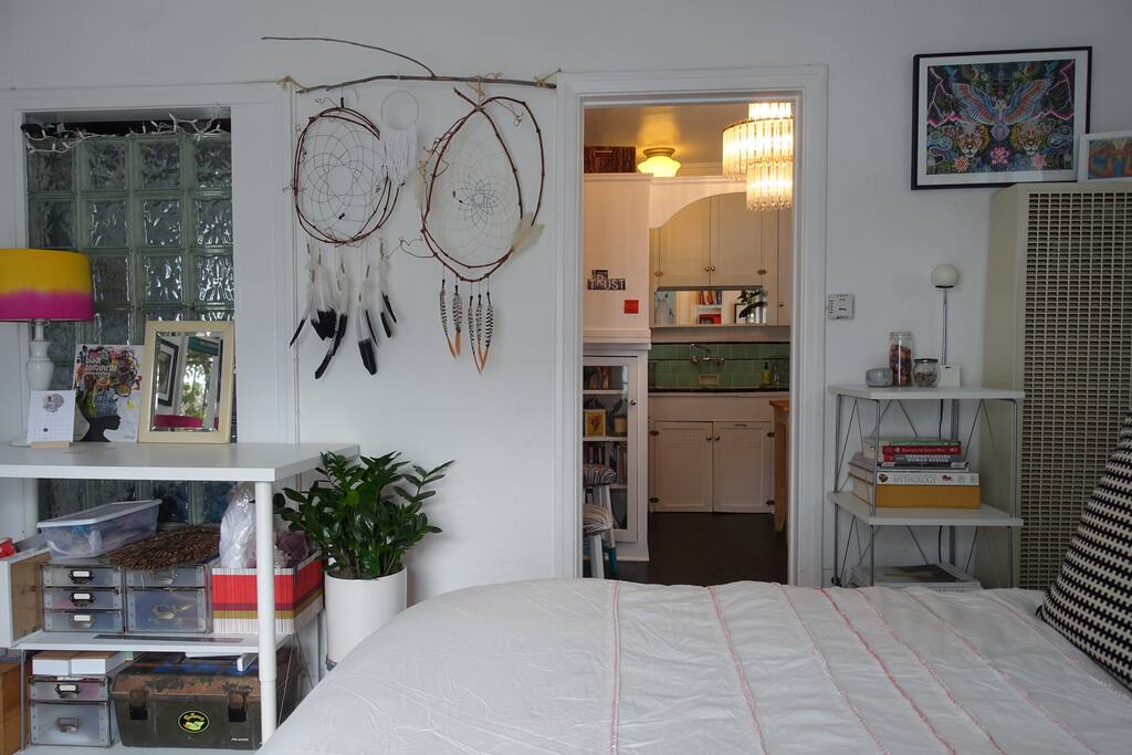 The kitchen is separate from the bright studio living. The bed is comfortable with multiple pillows to feel right at home.