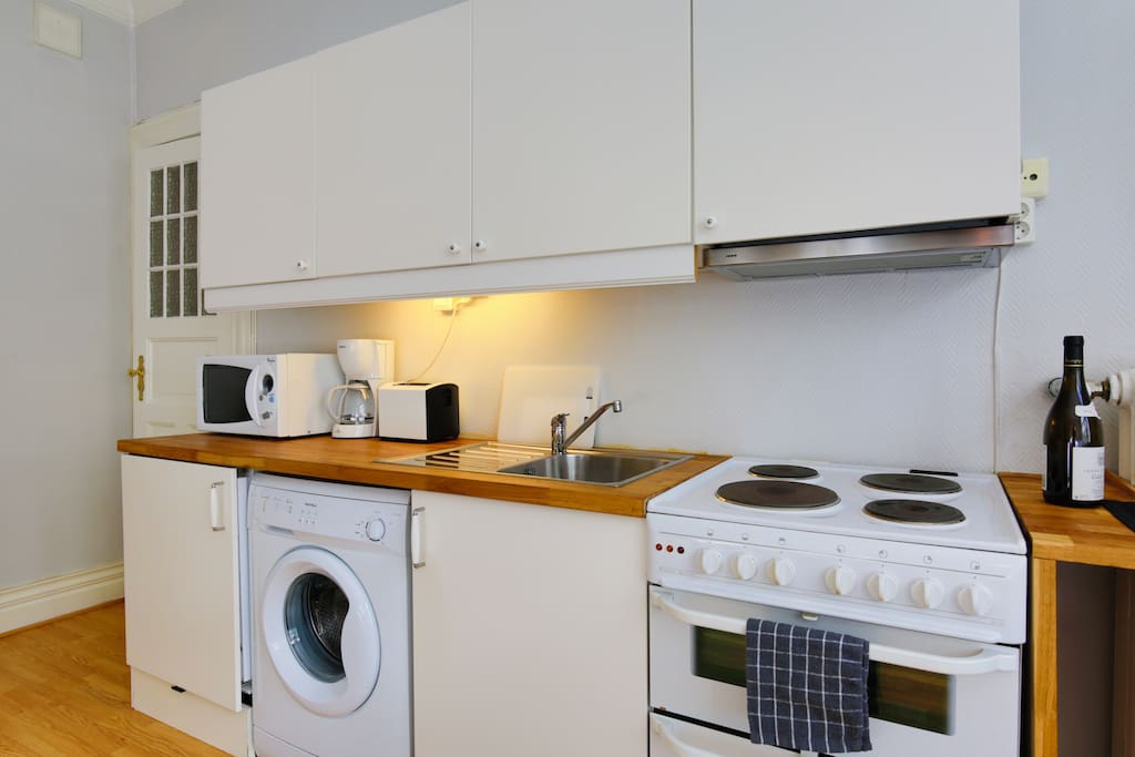 Kitchen area with stove, dishware, clothes washer, microwave, refrigerator and more. Enjoy a selection of coffee and tea as well!