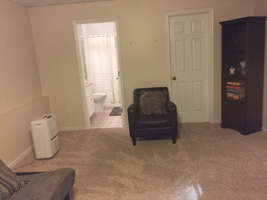 Opposite view of Bedroom with chair and doorway to bathroom.