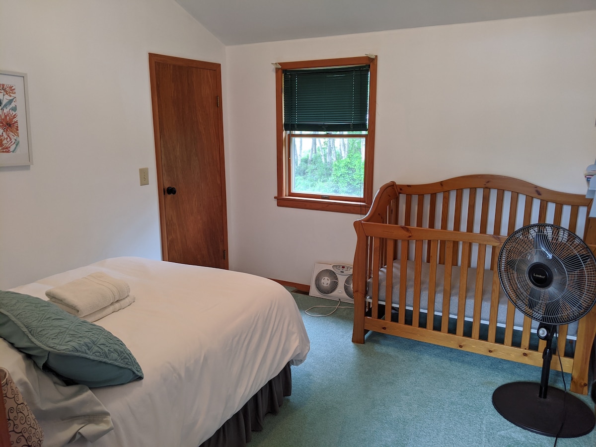 Kinderkamer boven met wieg en tweepersoonsbed. Raamventilator voor koeling.