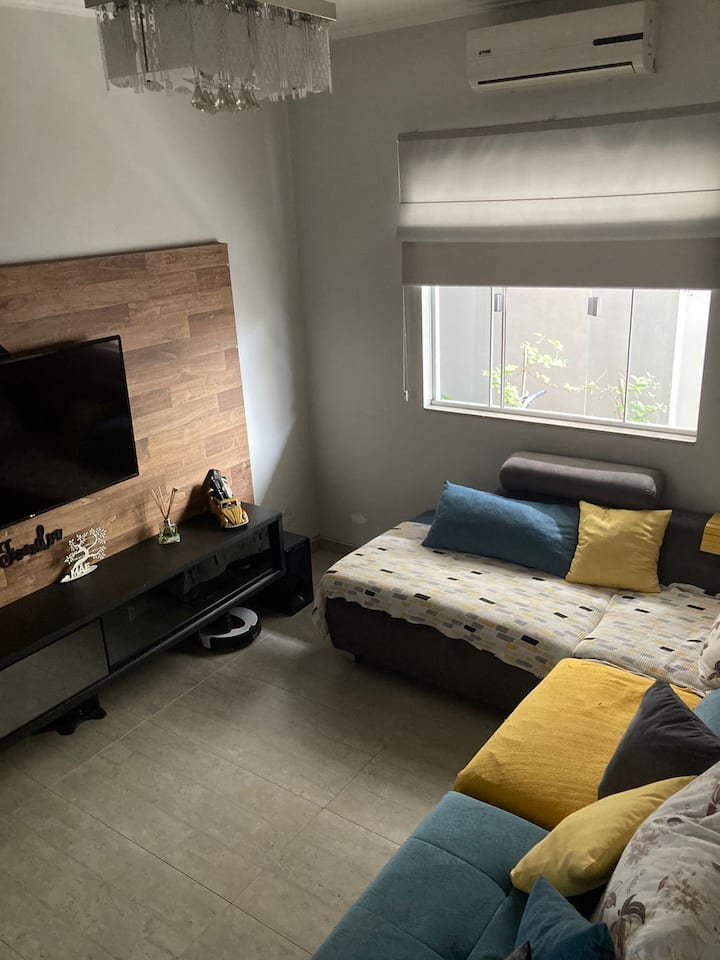 Habitación con un gran espacio en el sofá para colchones y acceso a la televisión, además del aire acondicionado.
