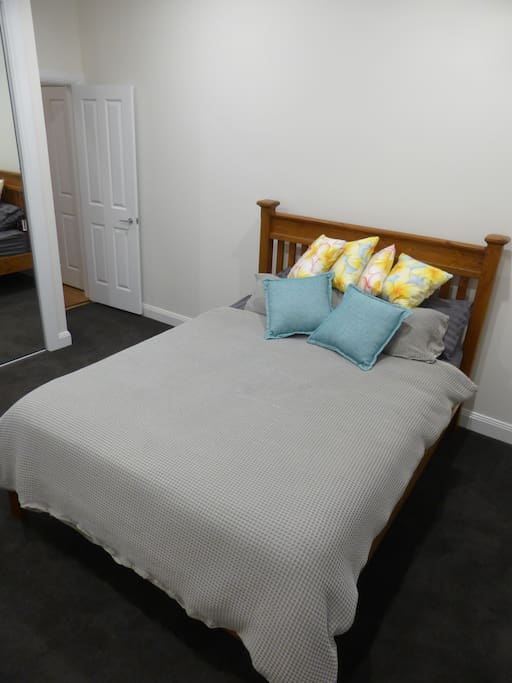 Comfortable queen size bed in a large bedroom with high ceilings and heating