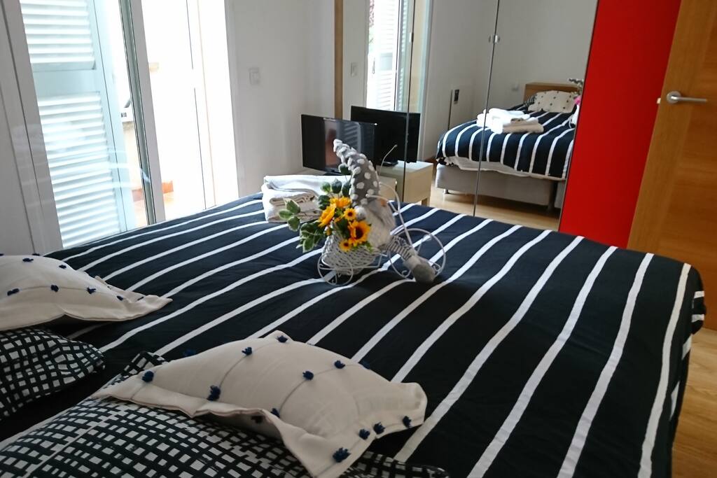 Luminoso dormitorio con cama extra grande de 180x200 cm. Amplio armarios empotrados y puertas de espejos. SMART TV con Chromecast y Google Home Mini para sacar máximo partido a sus gadgets y utilizar sus suscripciones a Spotify, Netflix, HBO, etc.