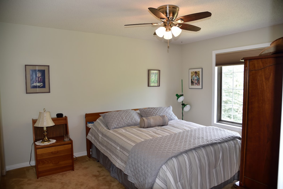 غرفة نوم تضم سرير 
كوين في الطابق العلوي ومروحة سقف وخزانة ملابس