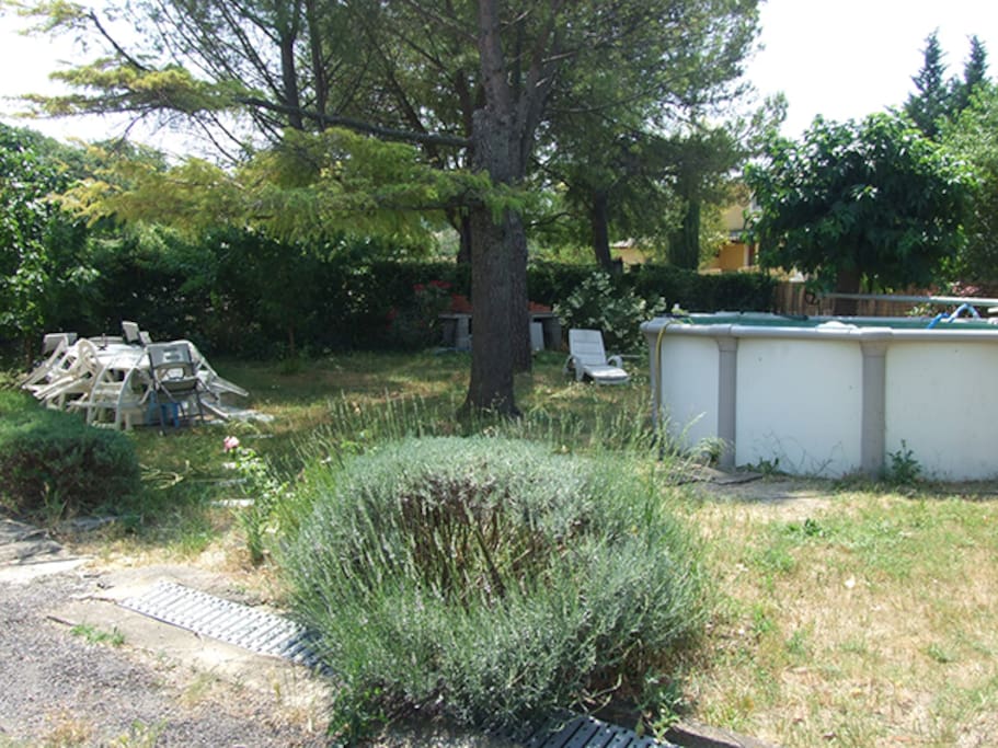Un jardin arboré avec un agréable espace terrasse, une piscine et une balançoire