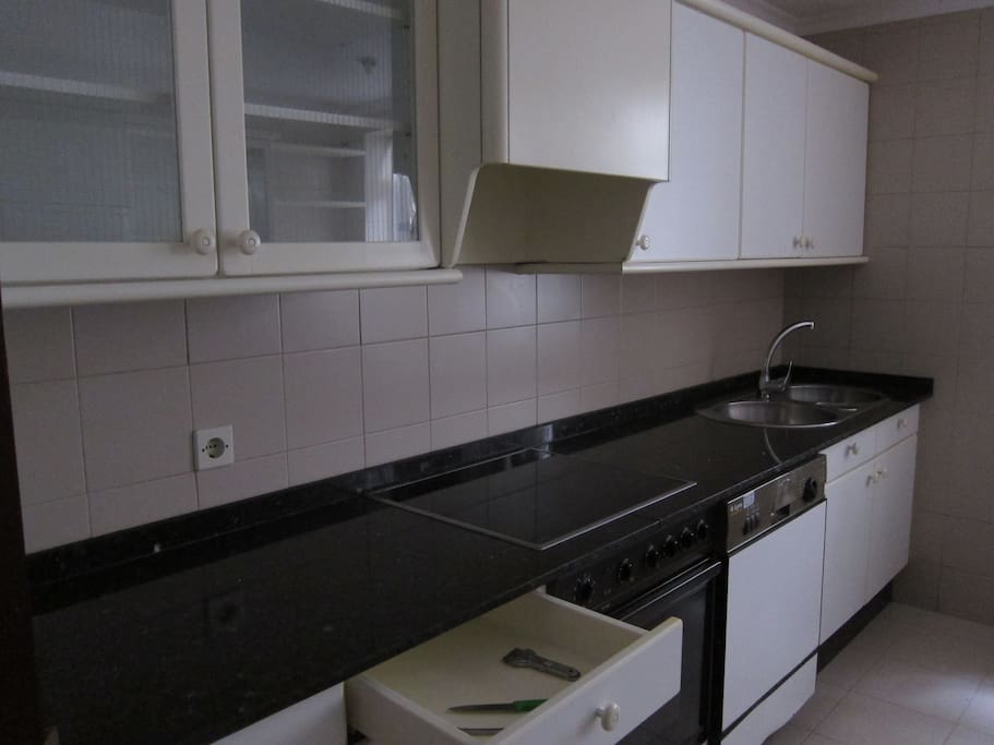 Cocina con placa vitrocerámica, lavadora, lavaplatos.