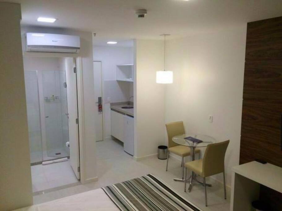 Quarto com boa iluminação, mesa para refeição e ar-condicionado
