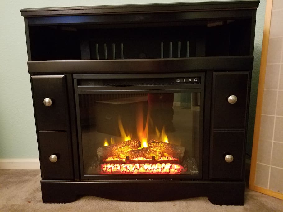 In-room electric fireplace with remote, timer & heat settings.