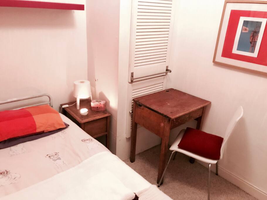 Bedroom with bedside table, desk, chair and wardrobe with shelving. Comfortable bed and pillow.