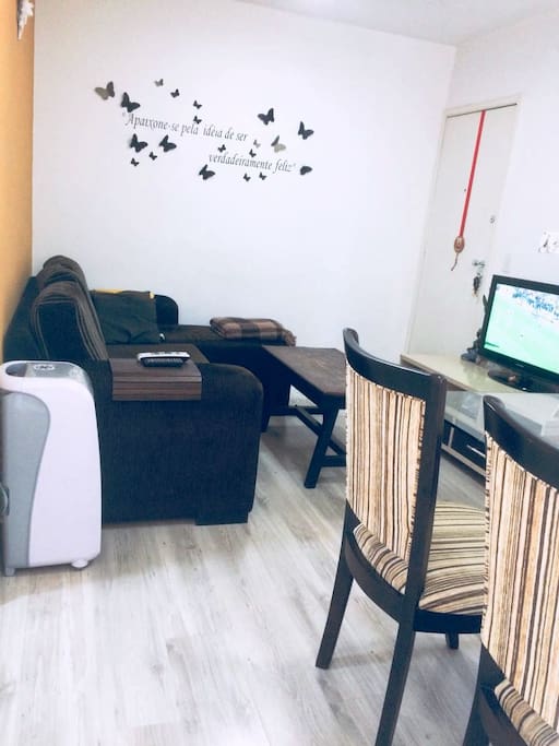 Sala de estar com TV, circulador de ar e aconchegante sofá.