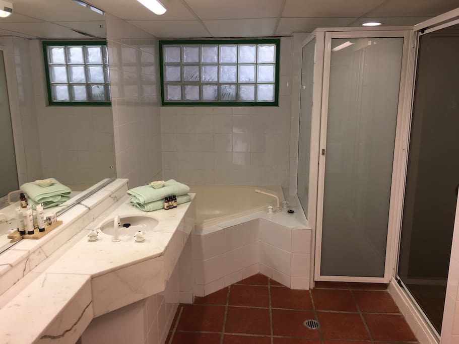 Bathroom with toilet, shower, bath, basin and hanging robe, as well as towels and toiletries