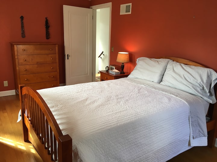 Light flooded master bedroom, with full-sized bed, upstairs overlooks the leafy (in summer) backyard. Walk out to a new deck with two chairs.