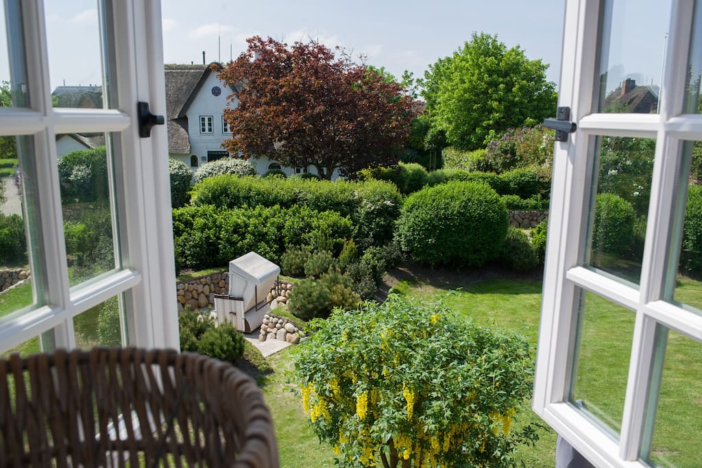 Blick aus dem Schlafzimmer auf den Südgarten mit Terrasse und Sonnenkuhle