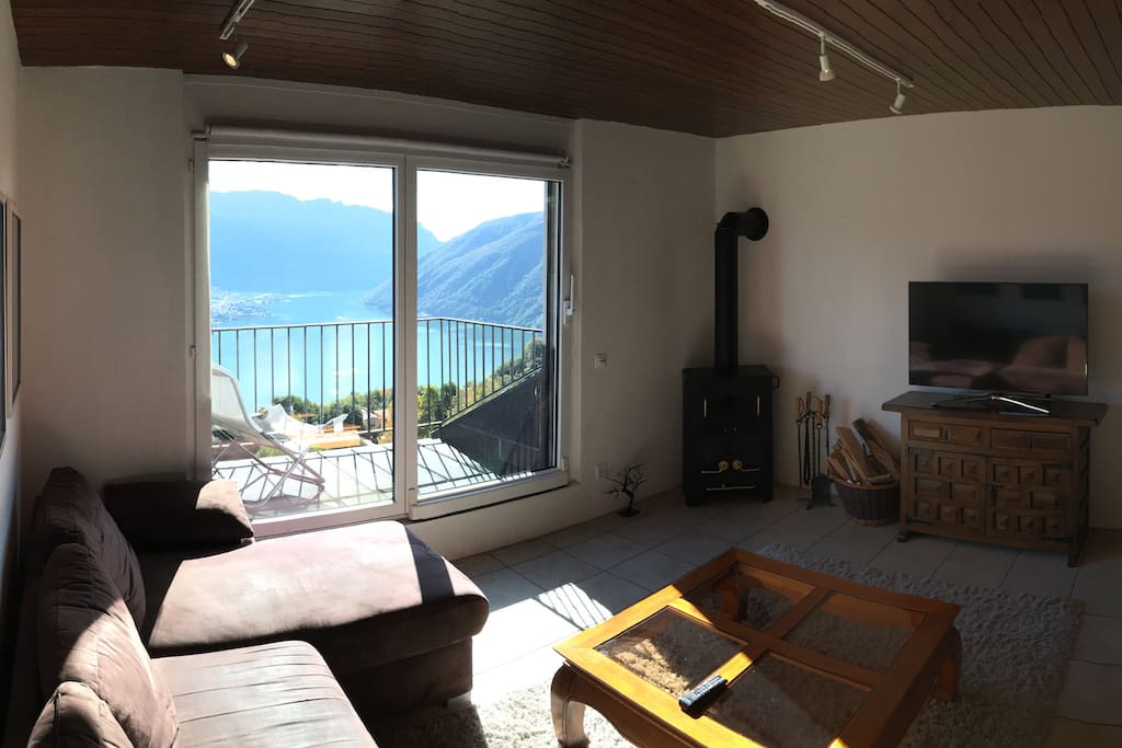 The living room with underfloor heating, wood burner, Samsung Smart TV, and fold-out sofa. Access to the balcony is via a large sliding door.