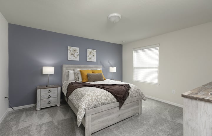 ¡Duerma profundamente en esta habitación de huéspedes bellamente decorada! Una pared decorativa de color gris pizarra enmarca una cama de madera clara con almohadas de color amarillo dorado y una acogedora cobija marrón, creando un espacio perfecto para relajarse.