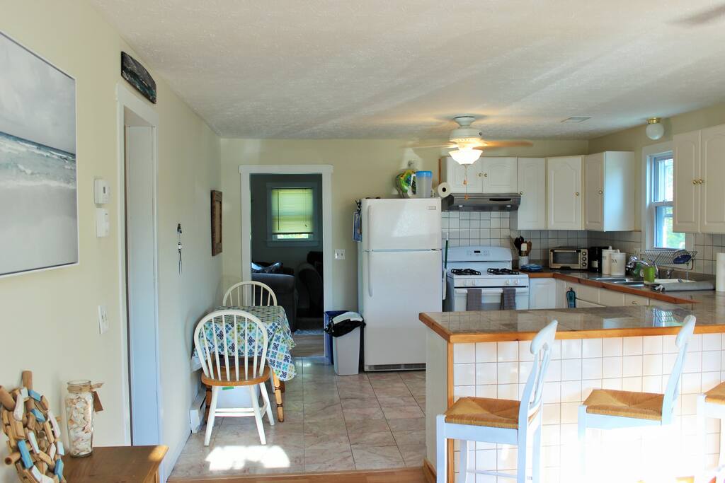 Open concept kitchen with seating for 8 at bar and drop-leaf table.