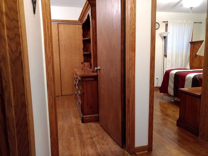 La vista desde el pasillo al dormitorio de invitados con cama de tamaño completo (doble o matrimonial) y al dormitorio principal con cama tamaño queen.