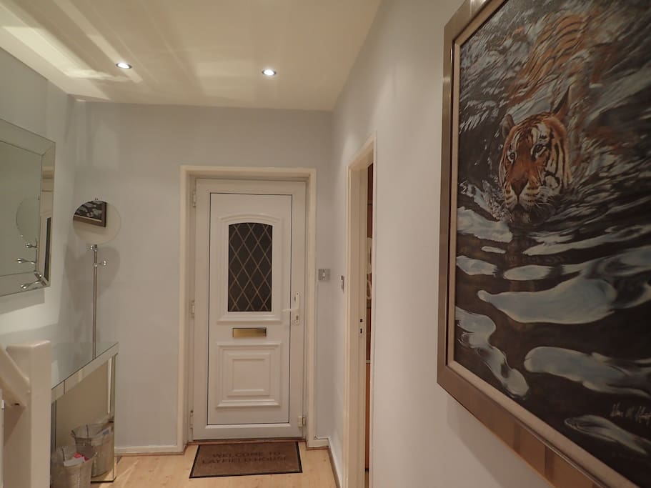 Brightly lit hallway with large vanity mirror, coat hanger & artwork