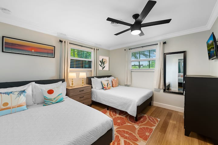 guest bedroom with two comfy double beds, smart tv, full length mirror, and usb charging lamps