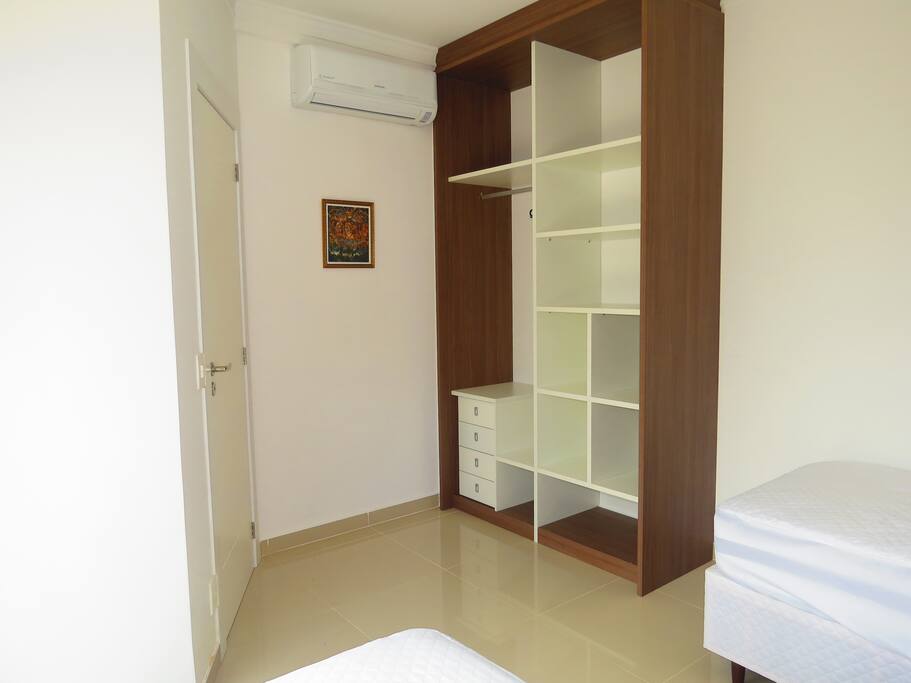 Quarto com duas camas de solteiro e armário.