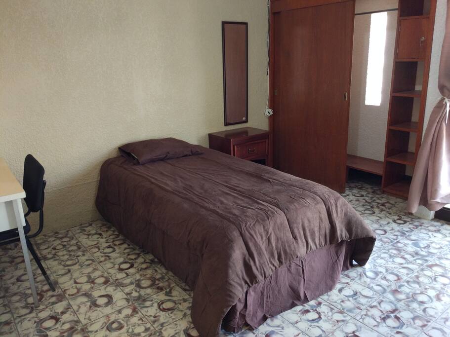Habitación con cama individual, closet con caja de seguridad, puff de descanso, escritorio y balcon