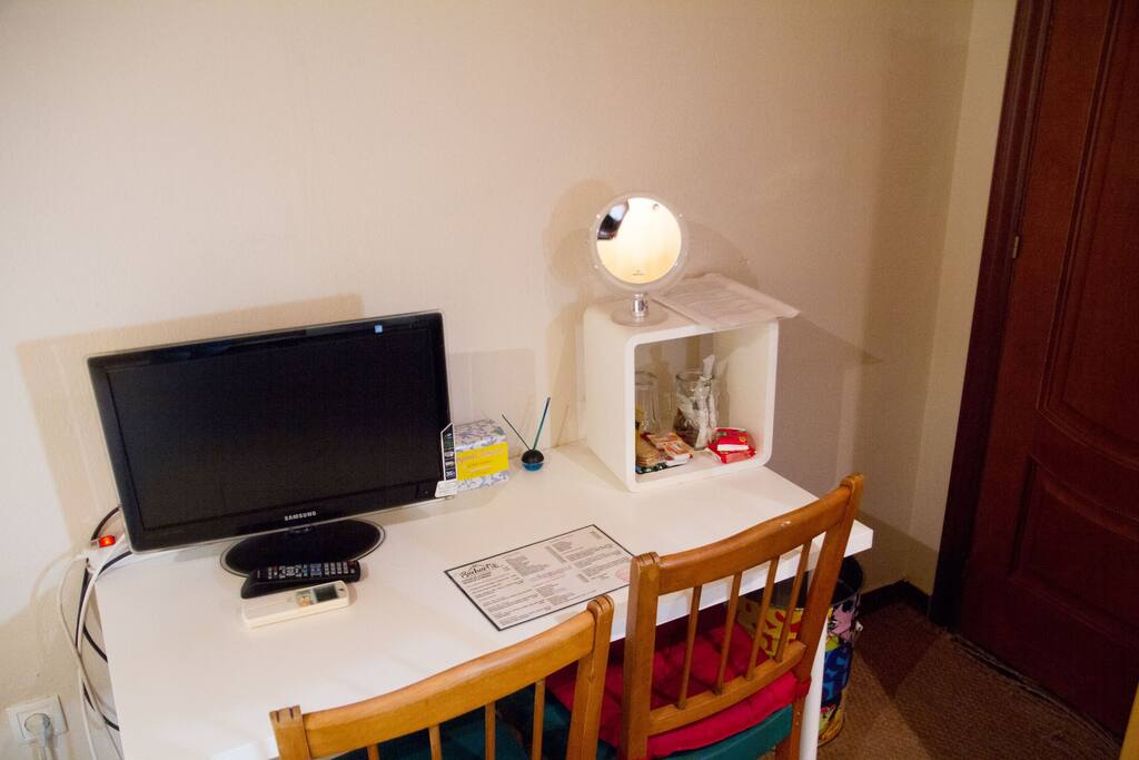 Mesa de escritorio con monitor de TV, regleta para otros aparatos eléctricos, espejo de aumento ideal maquillaje y sillas para su comodidad.