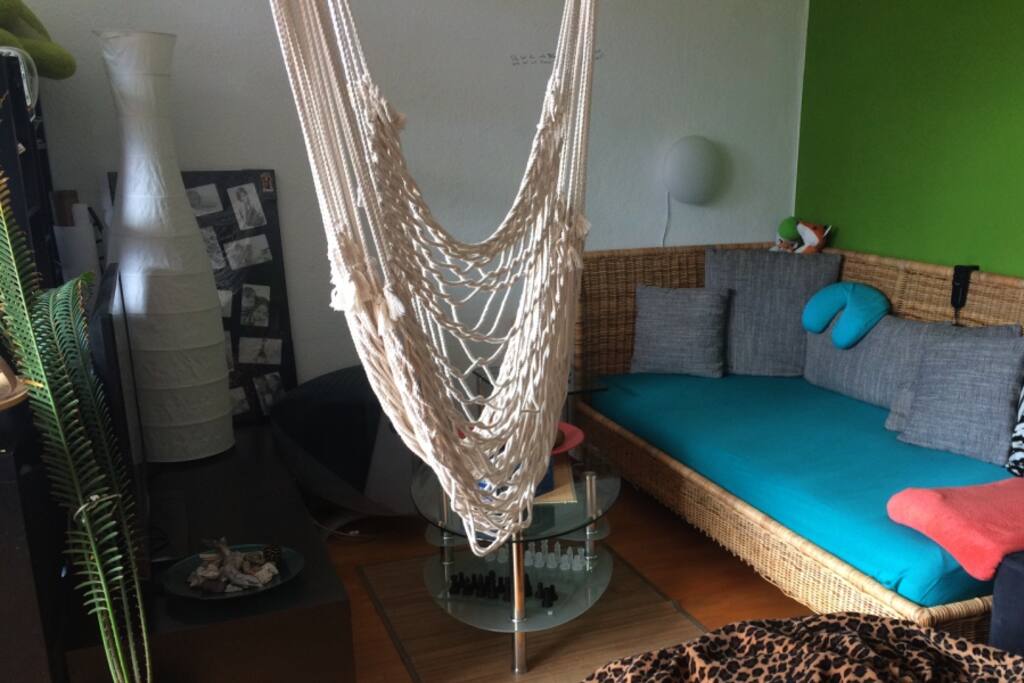 A TV corner with a big couch, a hammock and a beanbag chair.