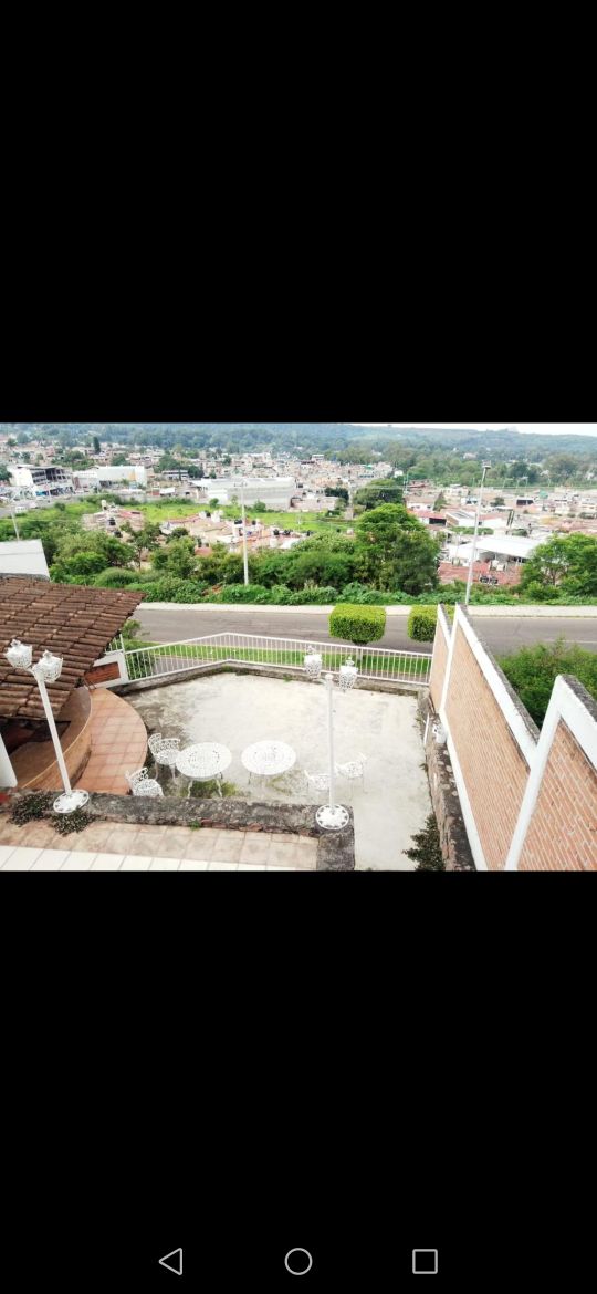 A spacious outdoor terrace is visible, featuring two small tables with chairs arranged for dining or relaxation. Scenic views of the surrounding landscape and neighborhood details can be observed, enhancing the outdoor experience. Clean, well-maintained surfaces surround the terrace area.