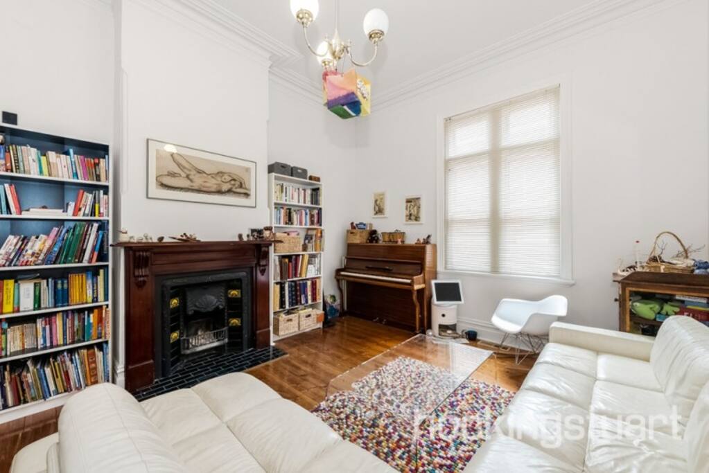 Cozy living room with white leather couch, fireplace, piano and books