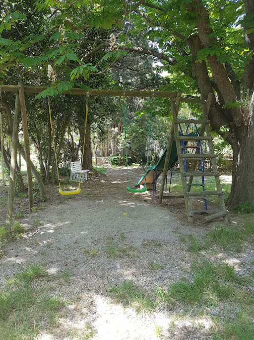 Grand jardin avec toboggan et balançoire accessible aux vacanciers.