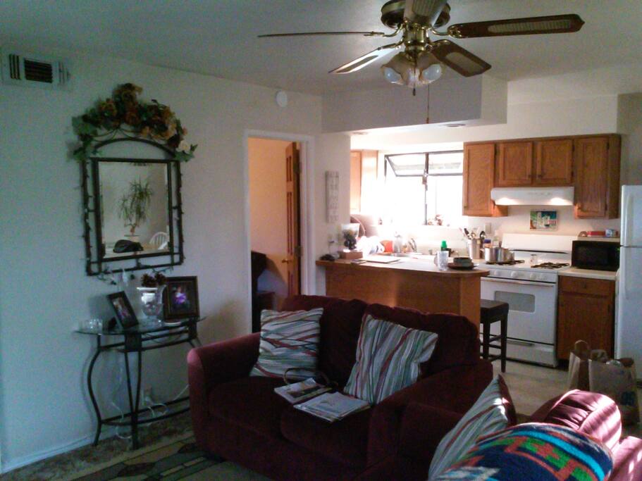 Kitchen with microwave, fridge, table for 2 and bar with 2 stools.