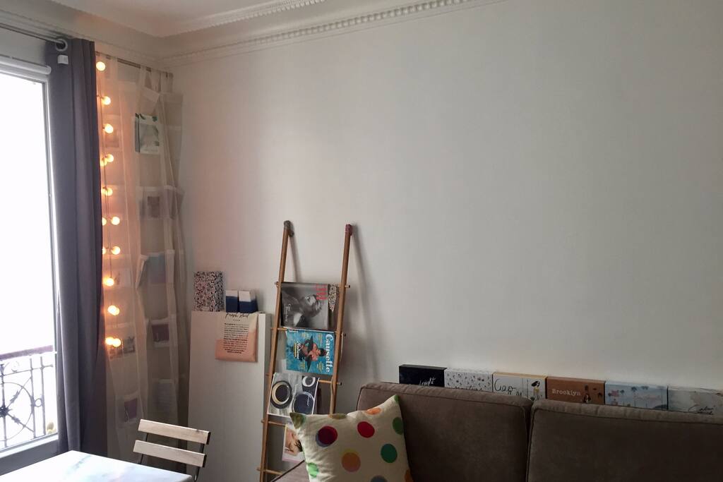 Pièce de vie avec canapé lit, une table et deux chaises, une fenêtre vue sur cour