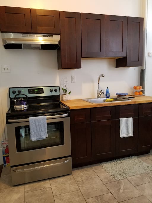 new renovated kitchen equipped with new range, refrigerator, pots, pans, cooking tools, and utensils