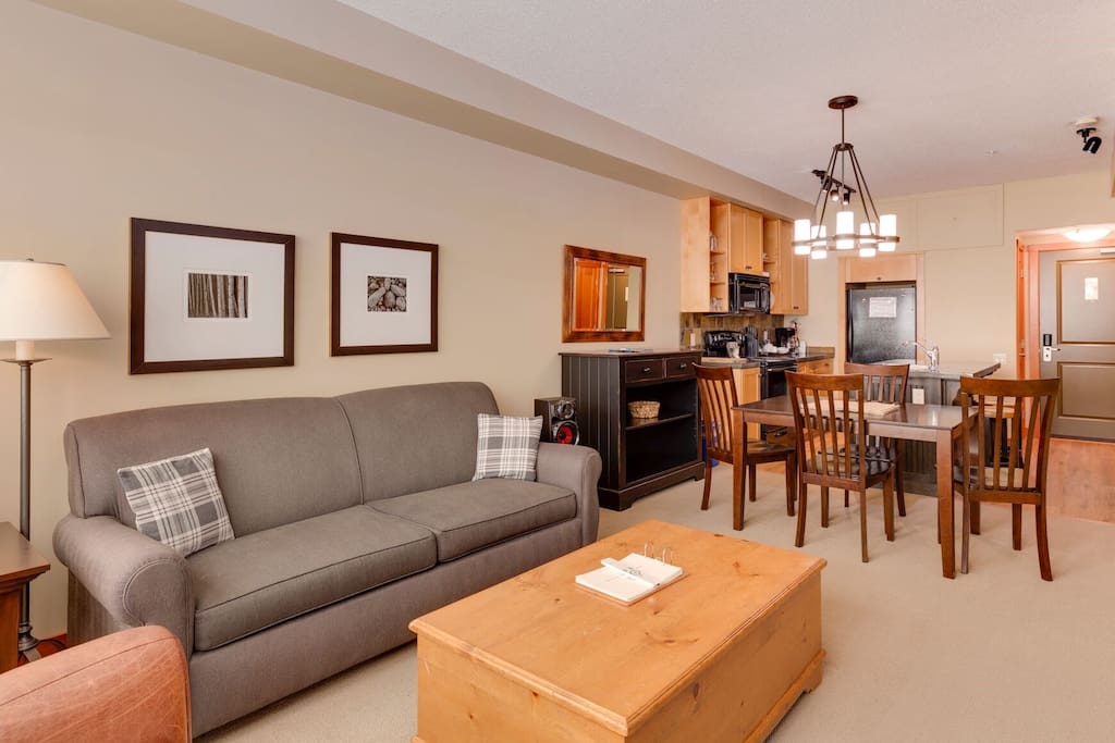 The living space is bright and open, featuring a sitting area, a dining table, and a TV.
