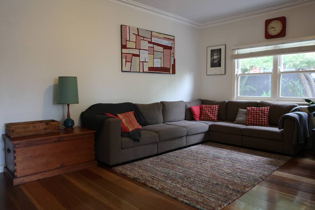 Light-filled open-plan living area with large couch and smart tv.