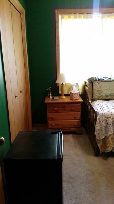 View of the mini fridge, night stand and closet.