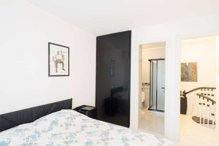 ห้องนอนใหญ่บนชั้นบนมีห้องน้ำพร้อมโถสุขภัณฑ์โถสุขภัณฑ์และฝักบัว