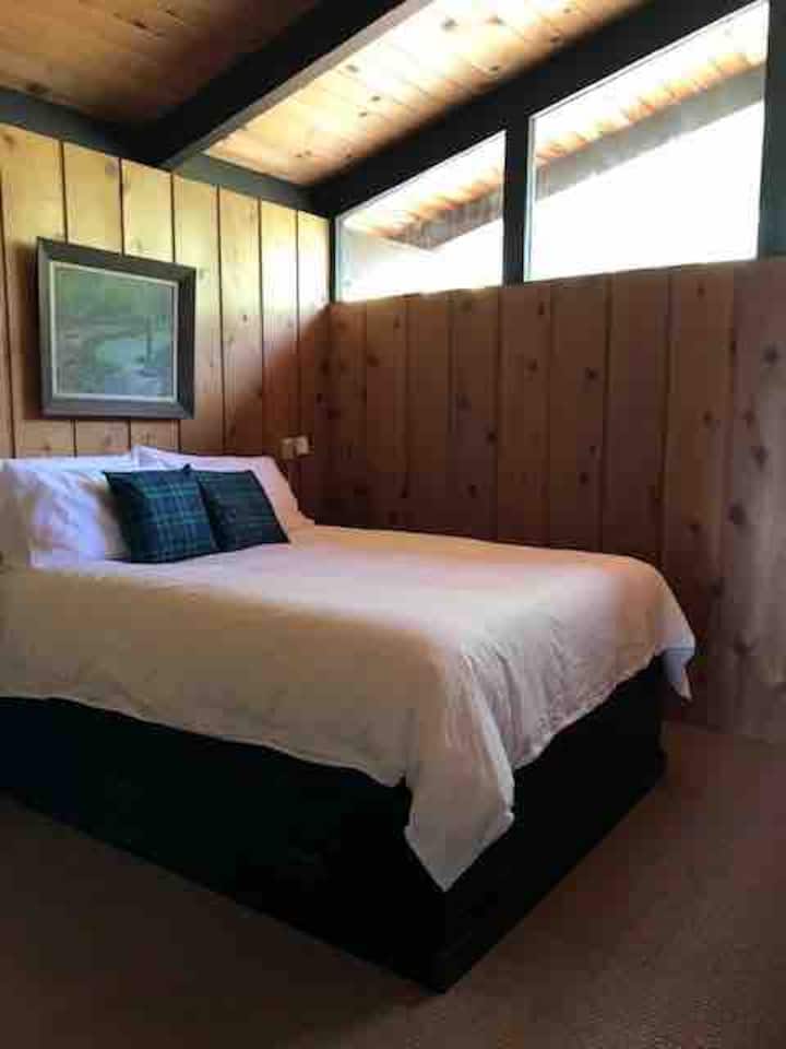 Средната спалня, двойно легло с разтегателен прозорец с изглед към върха на дърветата