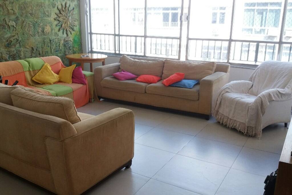 Sala ampla, com 3 sofás de lugares, poltrona de leitura, com ambiente de jantar e mesa de 6 lugares
