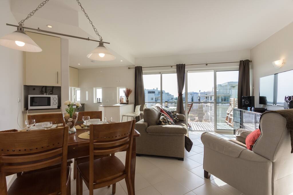 Overview of living room, dining area with kitchen and balcony in background
