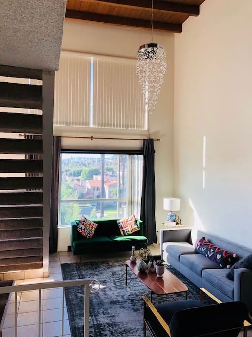 Living room with stairs leading to the den and the open terrace and 22 ft high ceilings