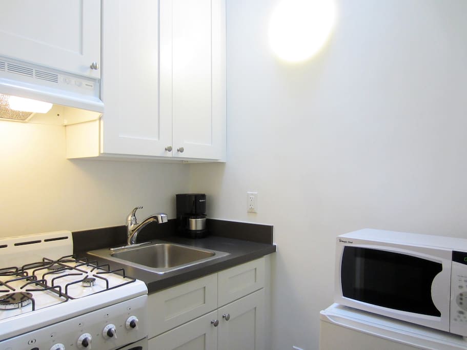 Stocked kitchen with gas range, a small refrigerator, and a microwave oven