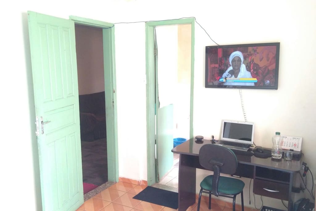 Suíte com cama de casal, tv a cabo, espaço de trabalho, ventilador, espaço para armazenamento de roupas.