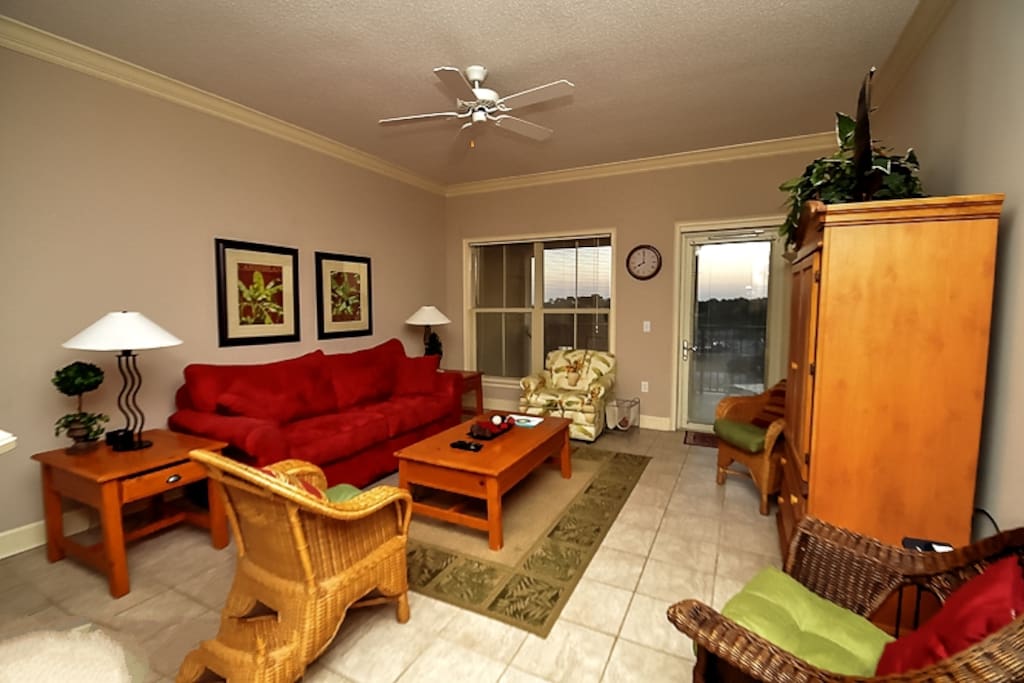 Living room has flat screen TV and access to the balcony with views of the ocean in the distance.