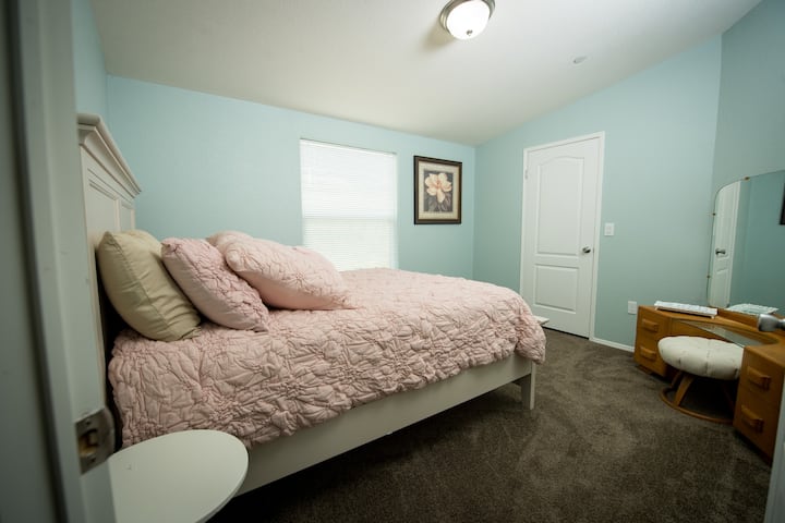 Guest bedroom with Queen size bed, night stand, mirror, luggage  rack in closet and a vintage 1940's vanity for extra room to get ready for your festivities. You will sink into this comfy pale pink bed and dream the night away.